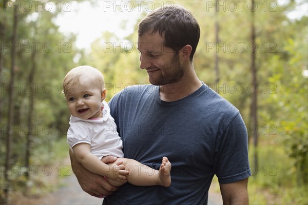 Happy mid adult man carrying baby daughter on forest track