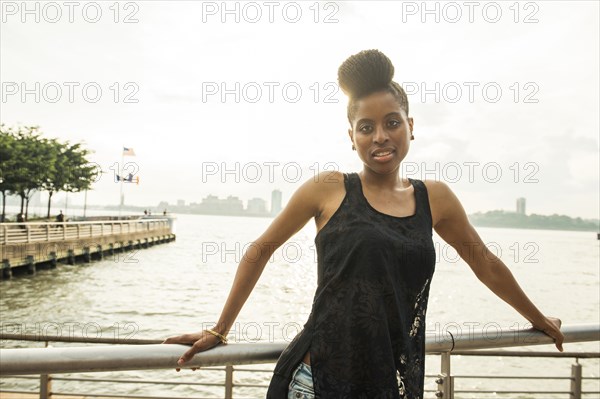 Portrait of African American woman leaning on railing at waterfront