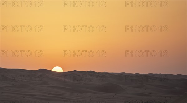 Sunrise over sand dunes in desert landscape