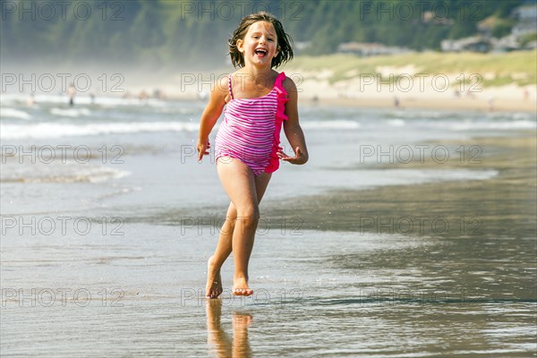 Caucasian girl playing in surf on beach