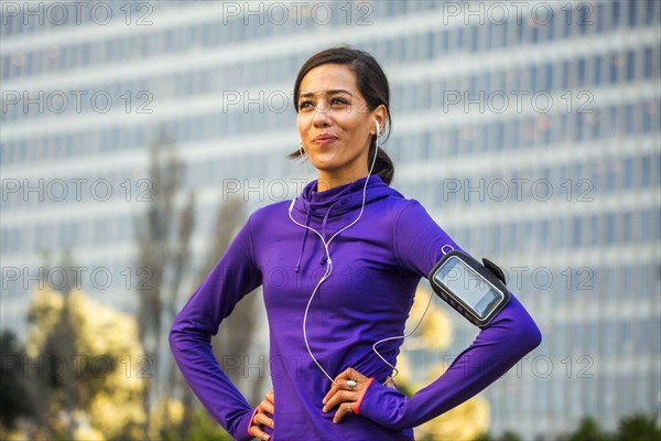 Hispanic runner standing near high rise building