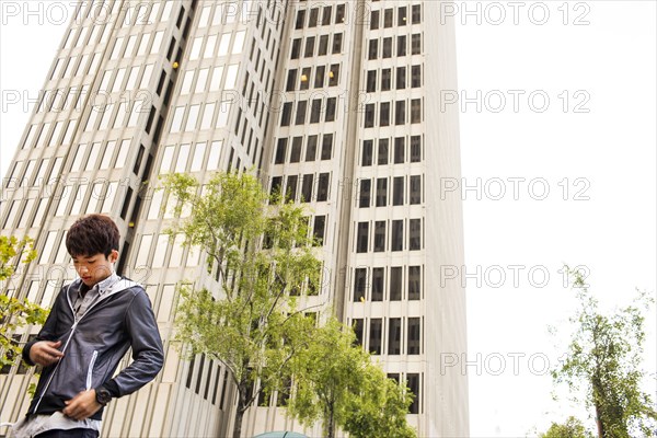 Asian man standing near urban skyscraper