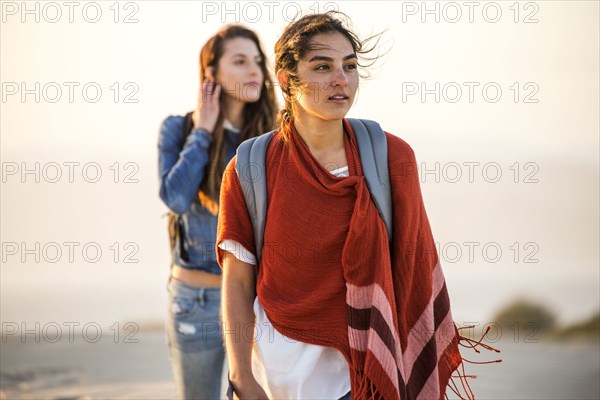 Mixed race women walking on beach