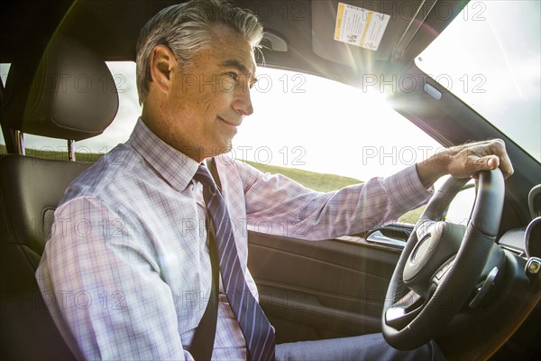 Smiling Caucasian businessman driving car