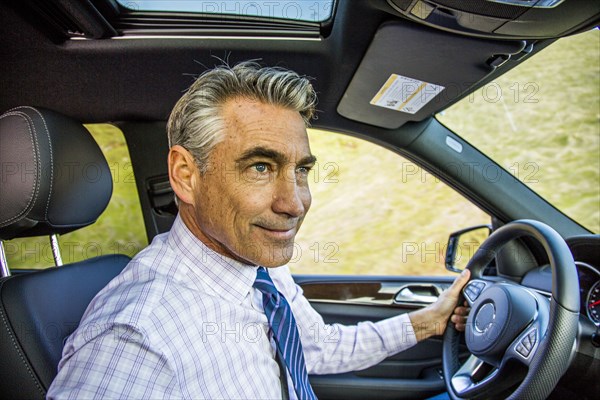 Smiling Caucasian businessman driving car