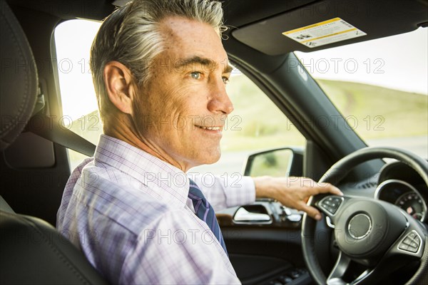 Smiling Caucasian businessman driving car