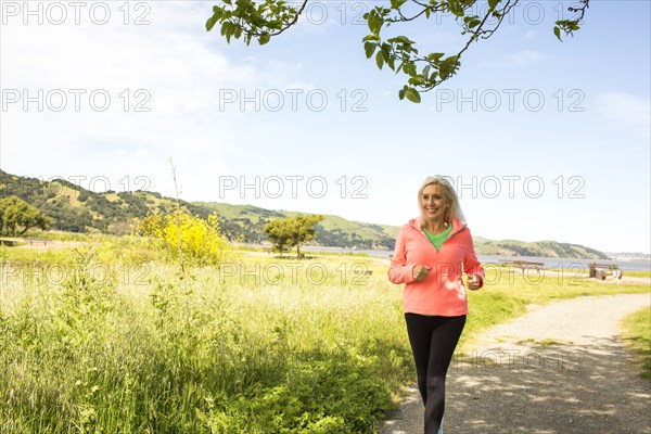 Older Caucasian woman running on path in park