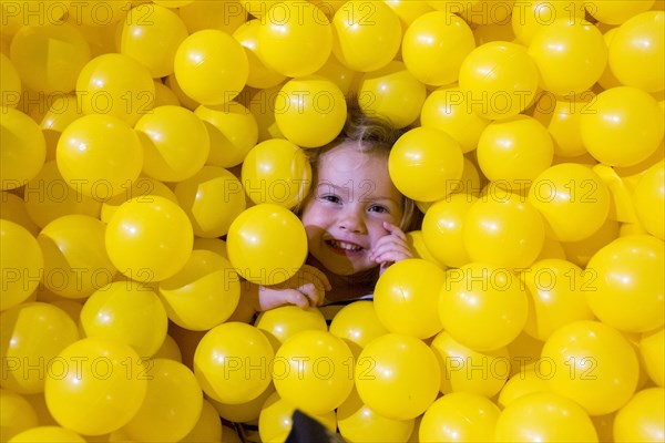 Caucasian girl laying in pile of yellow balls