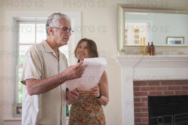 Caucasian couple reading paper in living room