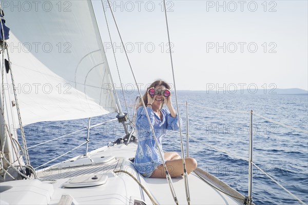 Caucasian woman using binoculars on boat deck