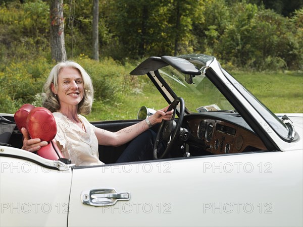 Older woman driving convertible in park