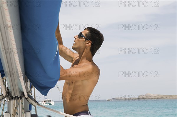 Man hoisting rigging on sailboat