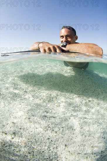 Close up of man laying on surfboard in ocean