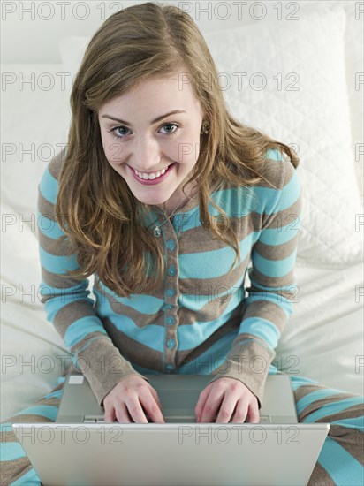 Caucasian woman using laptop on bed