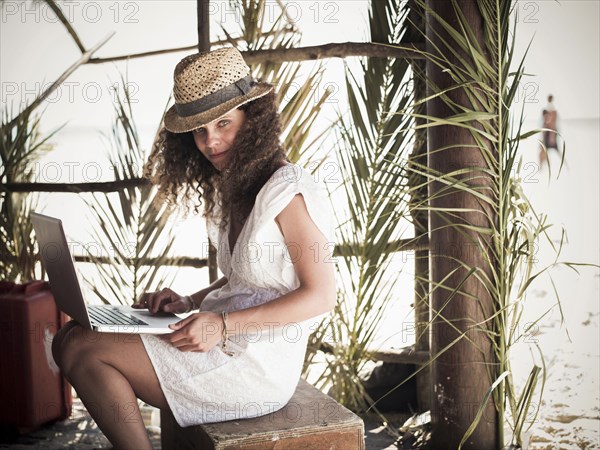 Woman using laptop in beach hut