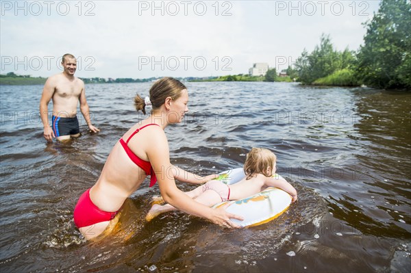 Caucasian family swimming in lake