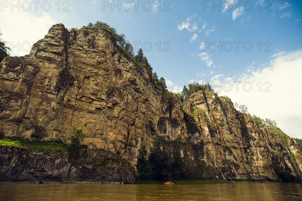 Distant boat on river near cliff