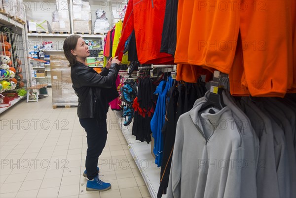 Caucasian woman examining shirt in store