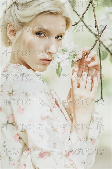 Middle Eastern woman smelling flowers on tree