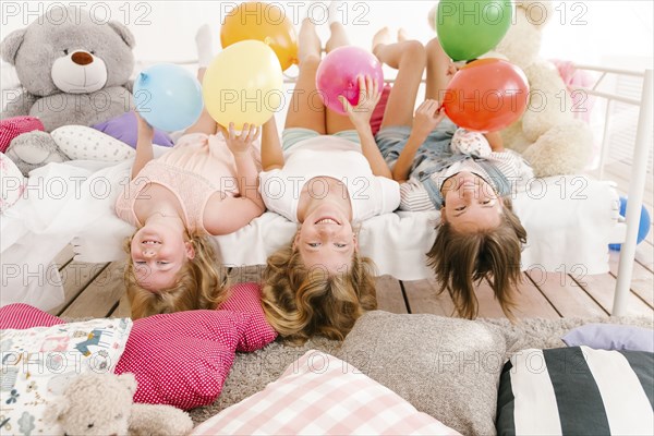 Portrait of smiling Middle Eastern sisters laying on bed