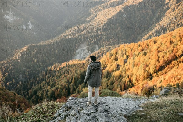 Caucasian man standing on mountain rock overlooking valley