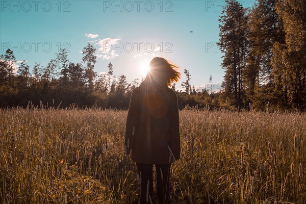 Wind blowing hair of woman standing in field