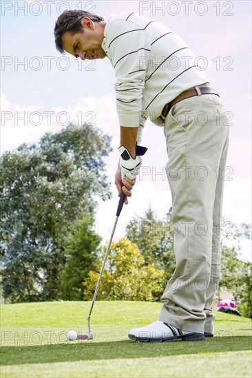 Hispanic man putting golf ball