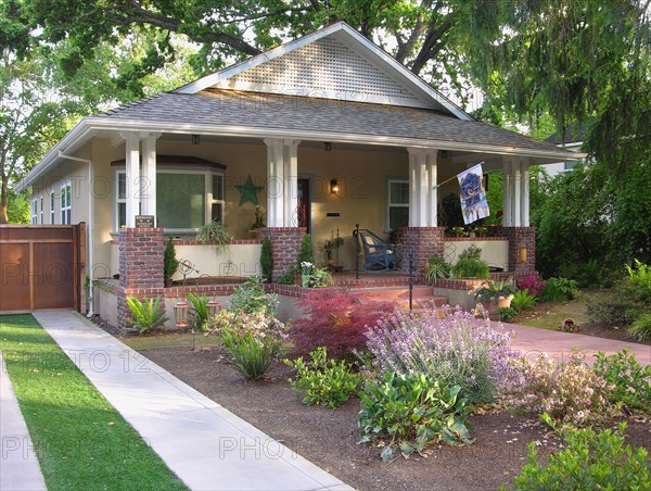 Front exterior yellow bungalow with white verandahs at Chico