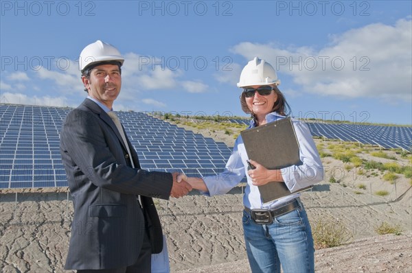 businessman shaking engineer's hand in solar plant