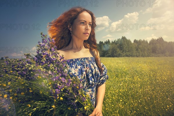 Caucasian woman holding flowers in rural field