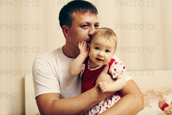 Caucasian father kissing baby daughter