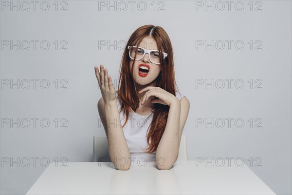 Caucasian Woman With Attitude Sitting At Table Wearing White Eyeglasses Photo12 Tetra Images
