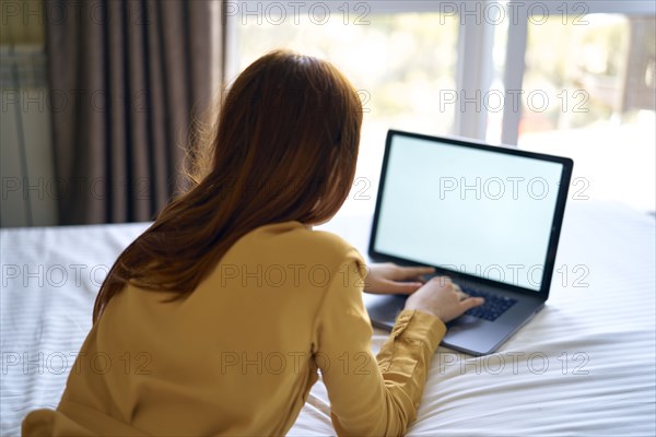 Caucasian woman laying on bed using laptop