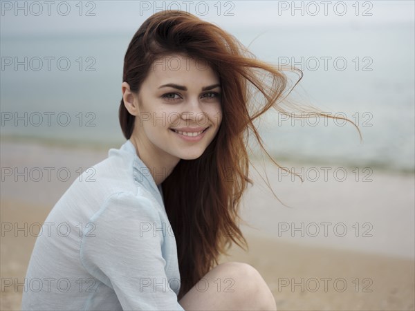 Wind blowing hair of Caucasian woman sitting on the beach