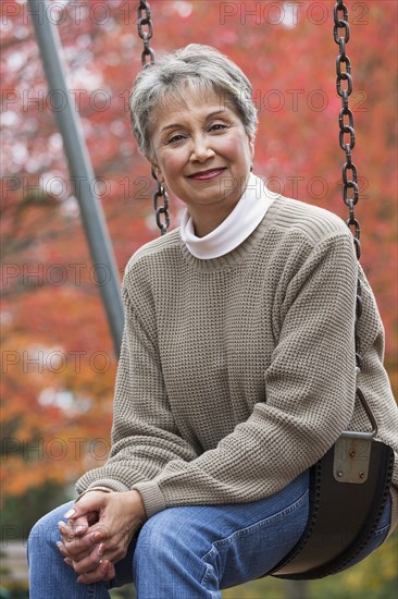 Mixed race woman on swing in park