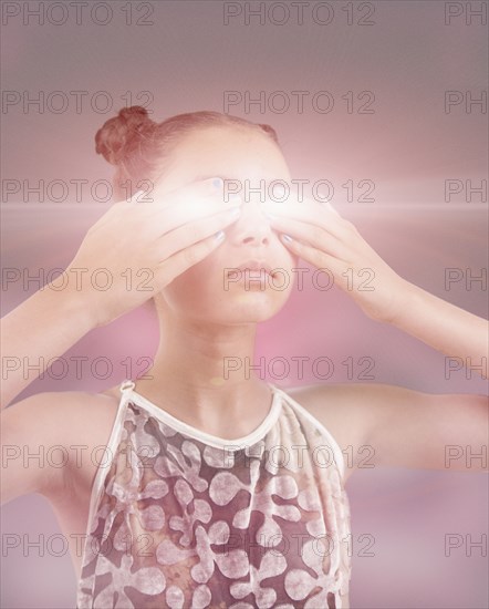 Mixed race girl covering glowing eyes