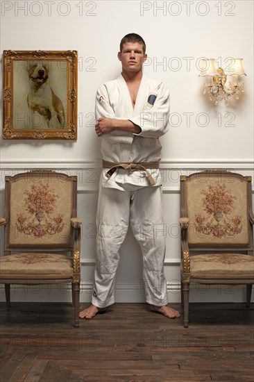 Serious Caucasian man in martial arts uniform standing in elegant room