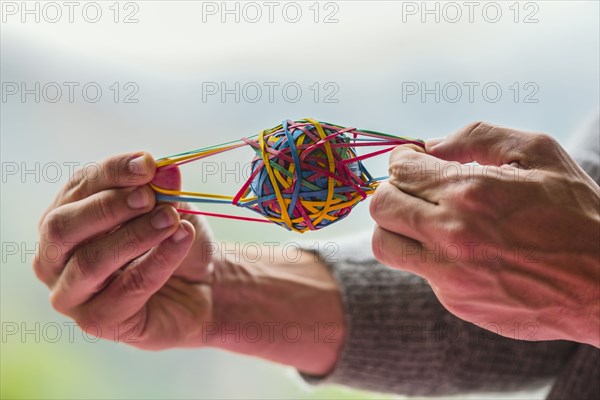 Close up of Caucasian man pulling rubber band ball