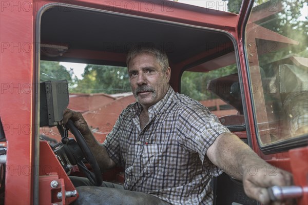 Caucasian man holding door of tractor