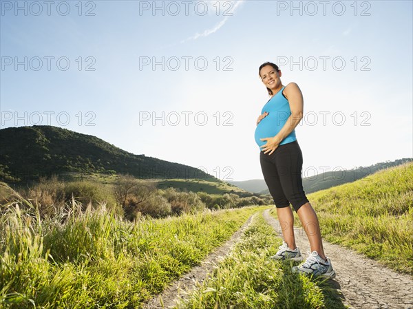 Pregnant Hispanic woman standing in remote area