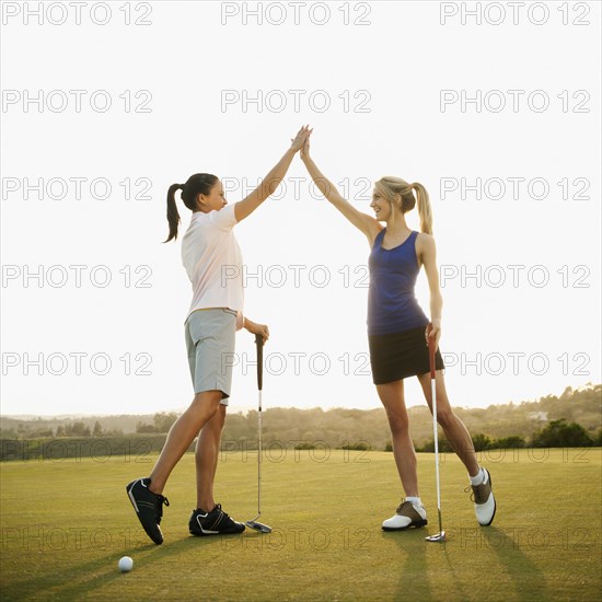 Women golfers high fiving on golf course
