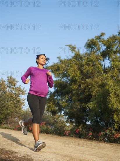 Pregnant Hispanic woman jogging outdoors