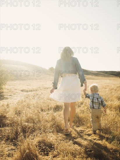 Caucasian mother and son walking in rural field