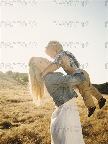 Caucasian mother and son hugging in rural field