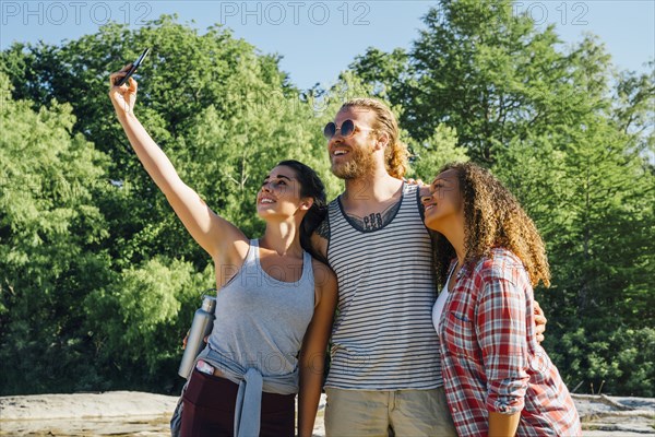 Friends posing for cell phone selfie outdoors