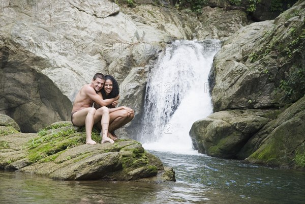 Couple swimming in pool near waterfall