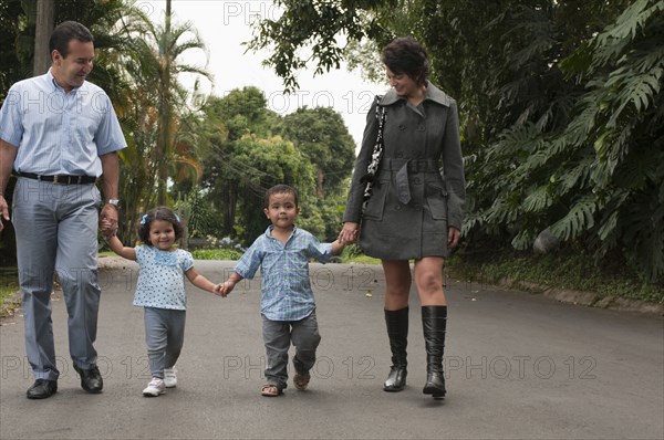 Hispanic parents holding children's hands outdoors