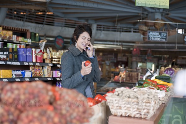 Hispanic woman talking on cell phone and shopping in grocery store