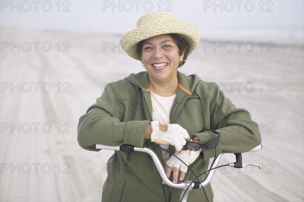 Senior woman with bicycle on beach