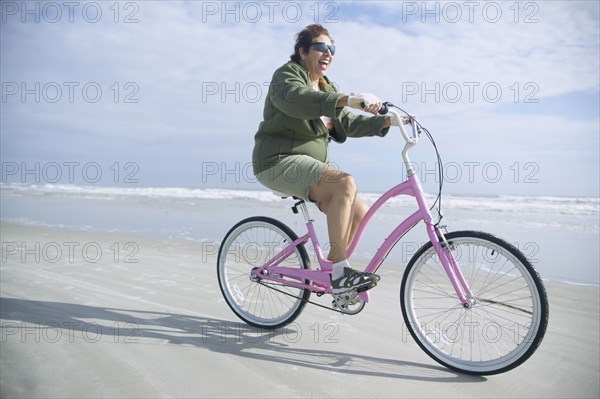 Senior Italian woman riding bicycle on beach